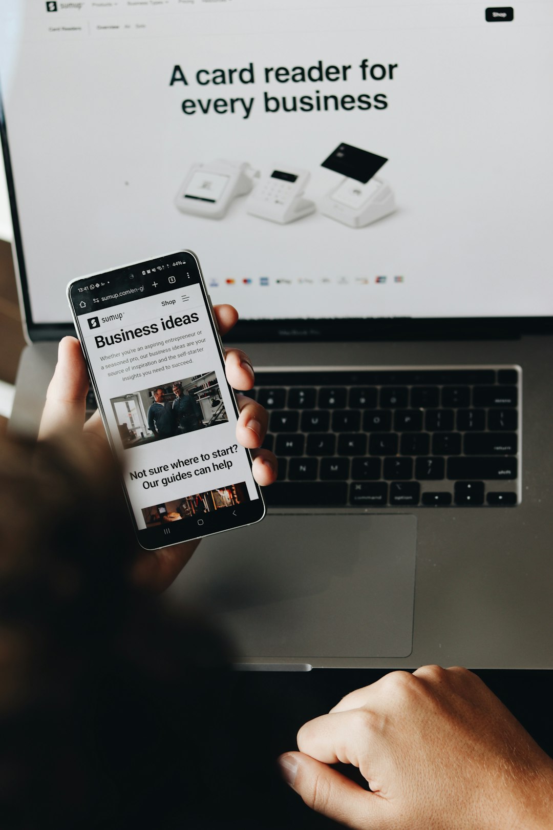 how-we-are A person is holding a smartphone displaying a page on business ideas. This image emphasizes the support SumUp provides to entrepreneurs and small business owners, helping them grow and manage their payment processes seamlessly.
